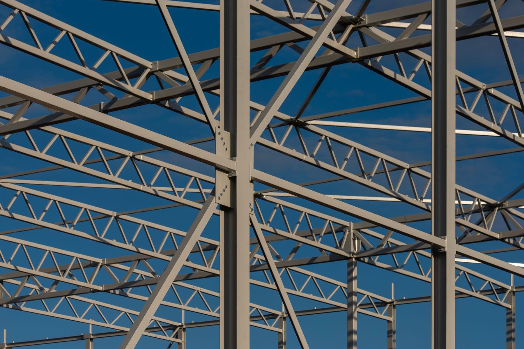 A gray painted steel truss frame against a deep blue sky.